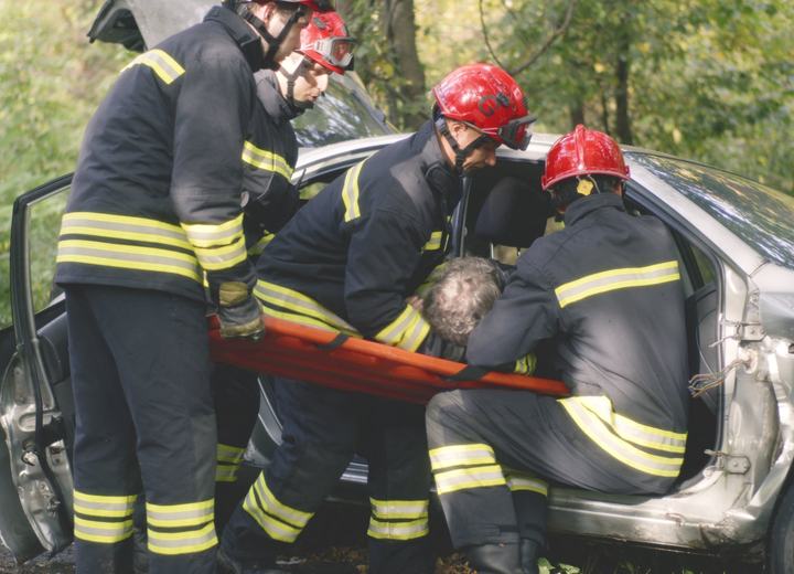 Firefighters rescuing an injured driver from a wrecked car